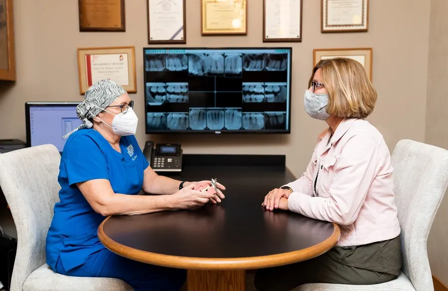A dentist at Davis & Engert going through a patient's x-rays with her at the consultation table.